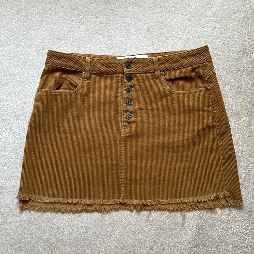 Corduroy button fly mini skirt with raw hem and working pockets.